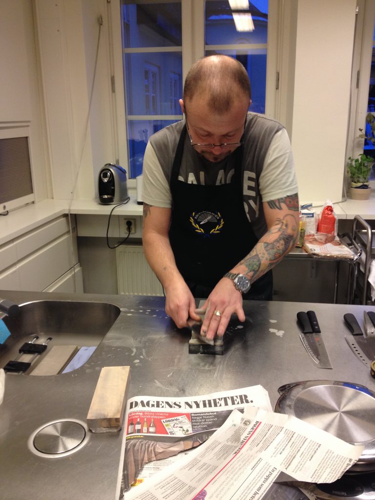 Pigge slipar knivar med van hand. Obs: man ska INTE testa skärpan på tidningar.