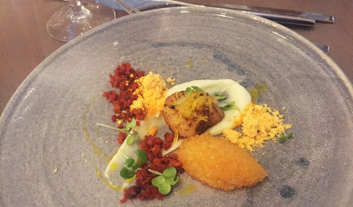 Pilgrimsmussla med blomkålscreme, syltad apelsin, salsiccia, sikrom och smör med skaldjursfond.