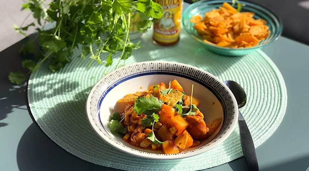 Tacogryta med kyckling serveras med valfria toppings. Jag tar koriander, smulade nachos och mexikansk chilisås.